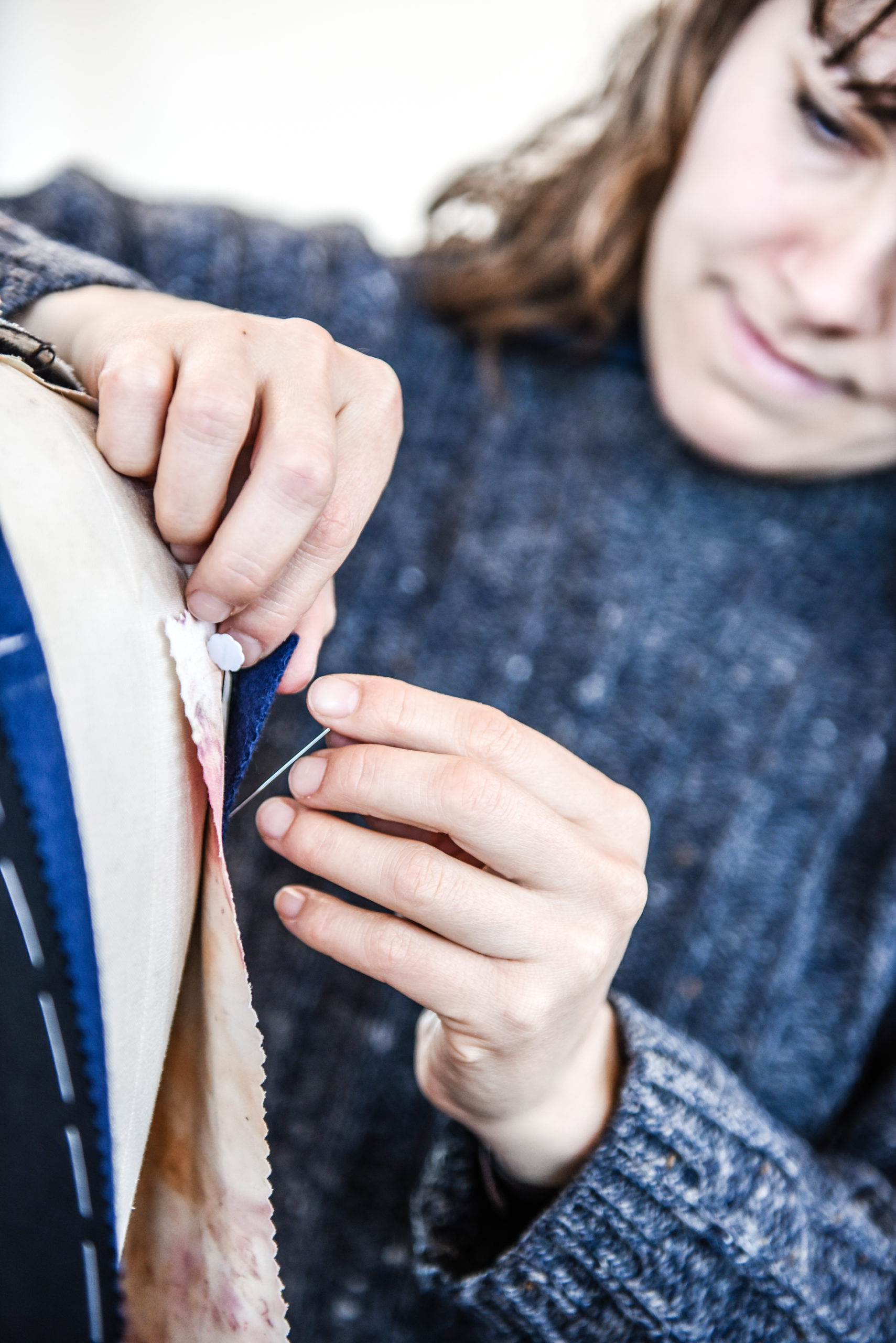The image shows a student learning to tailor a bespoke jacket