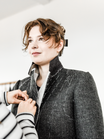 The picture shows a female student learning to fit a bespoke jacket.