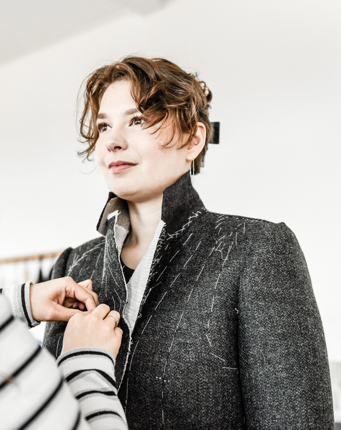 The picture shows a female student learning to fit a bespoke jacket.